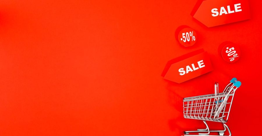 La spesa costa meno se pianifichi menu, offerte e prodotti base: Carrello della spesa con etichette in saldo su uno sfondo…
